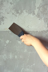 Woman's hand with a spatula plasters concrete wall