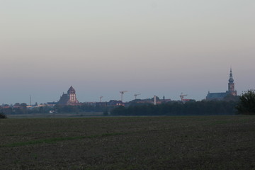 Fototapeta premium Meadows with misty view on the city of Greifswald, Mecklenburg-Vorpommern, Germany