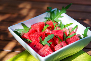 Delicious fresh watermelon and arugula salad on wooden table