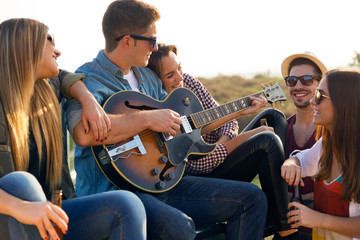 Portrait of group of friends playing guitar and drinking beer.