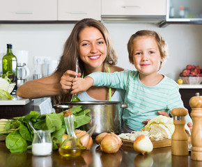 Mother with little daughter cooking at home