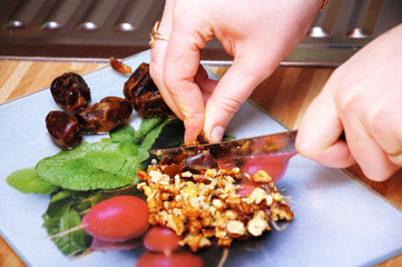 Woman hands cutting dates and walnut
