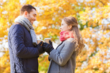 Fototapeta premium smiling couple with coffee cups in autumn park