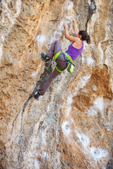 Fototapeta premium Young female rock climber on a face of a cliff