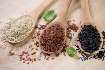 Wooden spoons with brown, red and black rice kernels, close-up