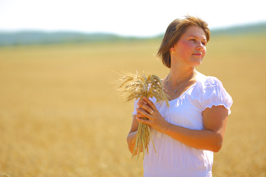 young woman posing in a field with wheat