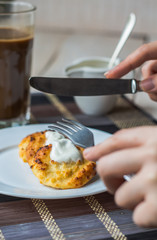 eat curd cheese pancakes with sour cream for breakfast, hands