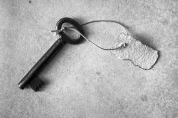 Old key with slip of paper on rustic paper, monochrome