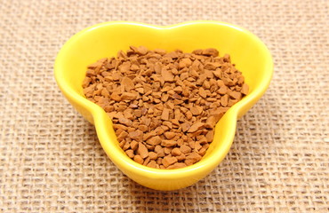 Instant coffee in yellow cup on jute canvas