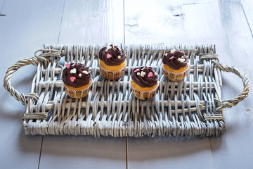 Four delicious chocolate cupcakes on a wicker tray