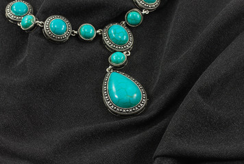 turquoise necklace on the black canvas - Powered by Adobe