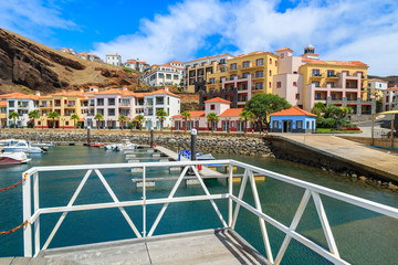 Wooden pier in marina with colorful houses, Madeira island