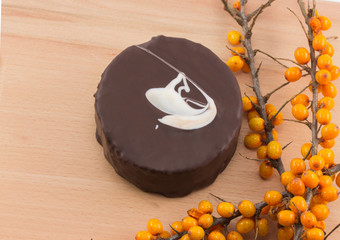 Chocolate cake and buckthorn on a wooden board