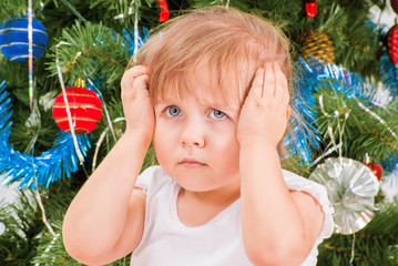 Upset and distraught little girl near the Christmas tree