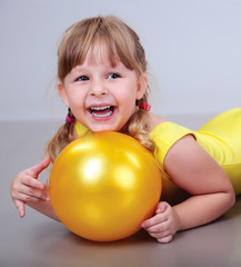 Fototapeta na wymiar baby girl in gymnastic clothes with ball laughs
