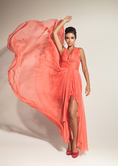 elegant fashion woman fluttering her coral dress