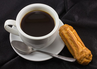 cup of coffee and cake on black fabric