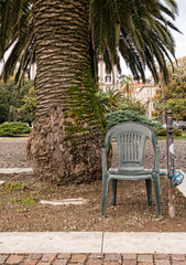 Anti theft device - chair padlocked to post. Under palm tree.