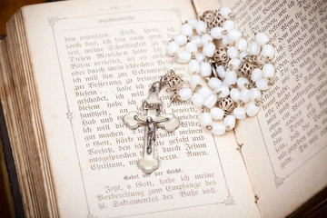 Rosenkranz mit Jesus an Kreuz auf Bibel Seiten