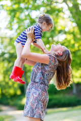 Beautiful young mother holding her happy little kid girl in arms