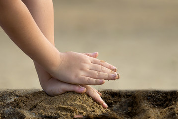 Child piling up the sand, so pat and press sand with two hand.cr
