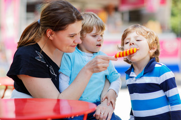 Mother feeding her little kid boys with ice cream