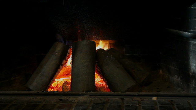 Wooden blocks burning in  the fireplace made from bricks