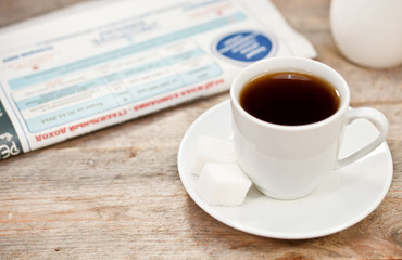 Cup of coffee and newspaper on a wooden table
