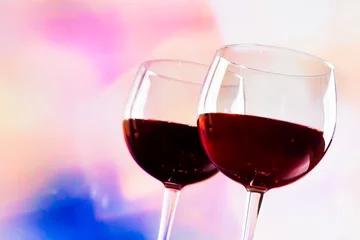 Fotobehang red wine glasses against colorful unfocused lights background © donfiore