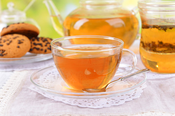 Teapot and cups of tea on table on bright background
