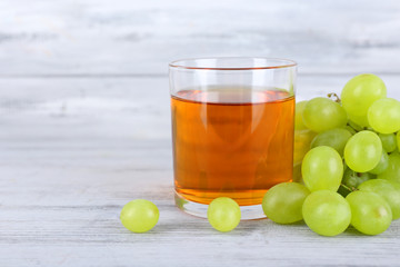 glass of juice with fresh grape on grey wooden table