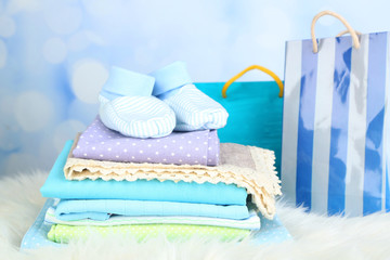 Baby clothes and gift bag on bright background