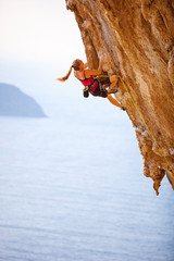 Female rock climber on cliff, Kalymnos Island, Greece