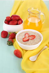 Tasty oatmeal with strawberry and juice on table close-up