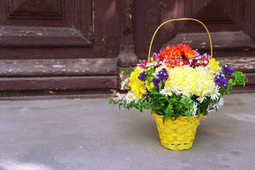 Flowers in basket on wooden door background
