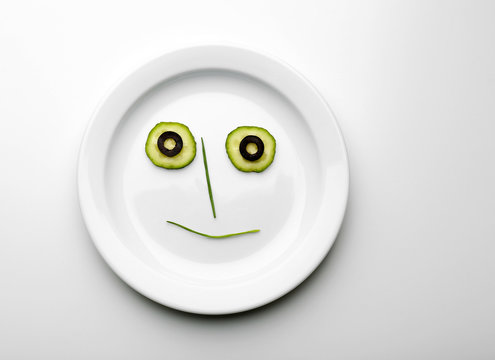 Vegetable face on plate isolated on white