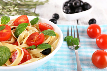 Spaghetti with tomatoes, olives and basil leaves