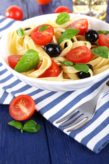 Spaghetti with tomatoes, olives and basil leaves
