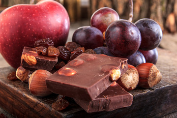 Chocolate pieces with nuts grapes and apple