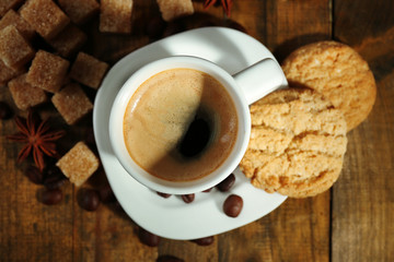 Cup of espresso and tasty cookie on wooden background