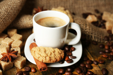 Cup of espresso and tasty cookie on wooden background