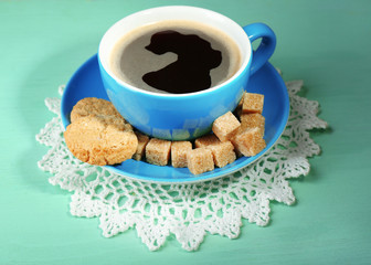 Glass cup of coffee and tasty cookie on color wooden background