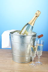 Bottle of champagne in metal ice bucket and two glasses