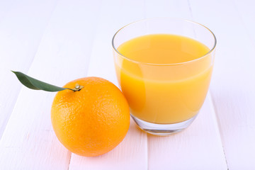 Glass of fresh orange juice on white wooden table