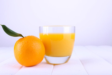 Glass of fresh orange juice on white wooden table