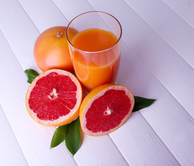 Grapefruit juice and fresh grapefruit on wooden table