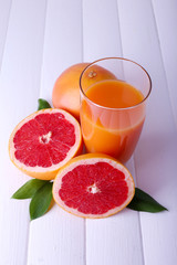 Grapefruit juice and fresh grapefruit on wooden table