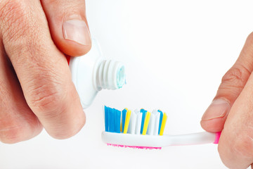 The tube of toothpaste and a toothbrush in hand man