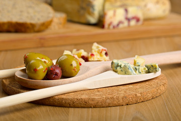 Olives and cheese on a wooden spoons
