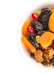 Mix variety of dried fruit in white bowl over white background